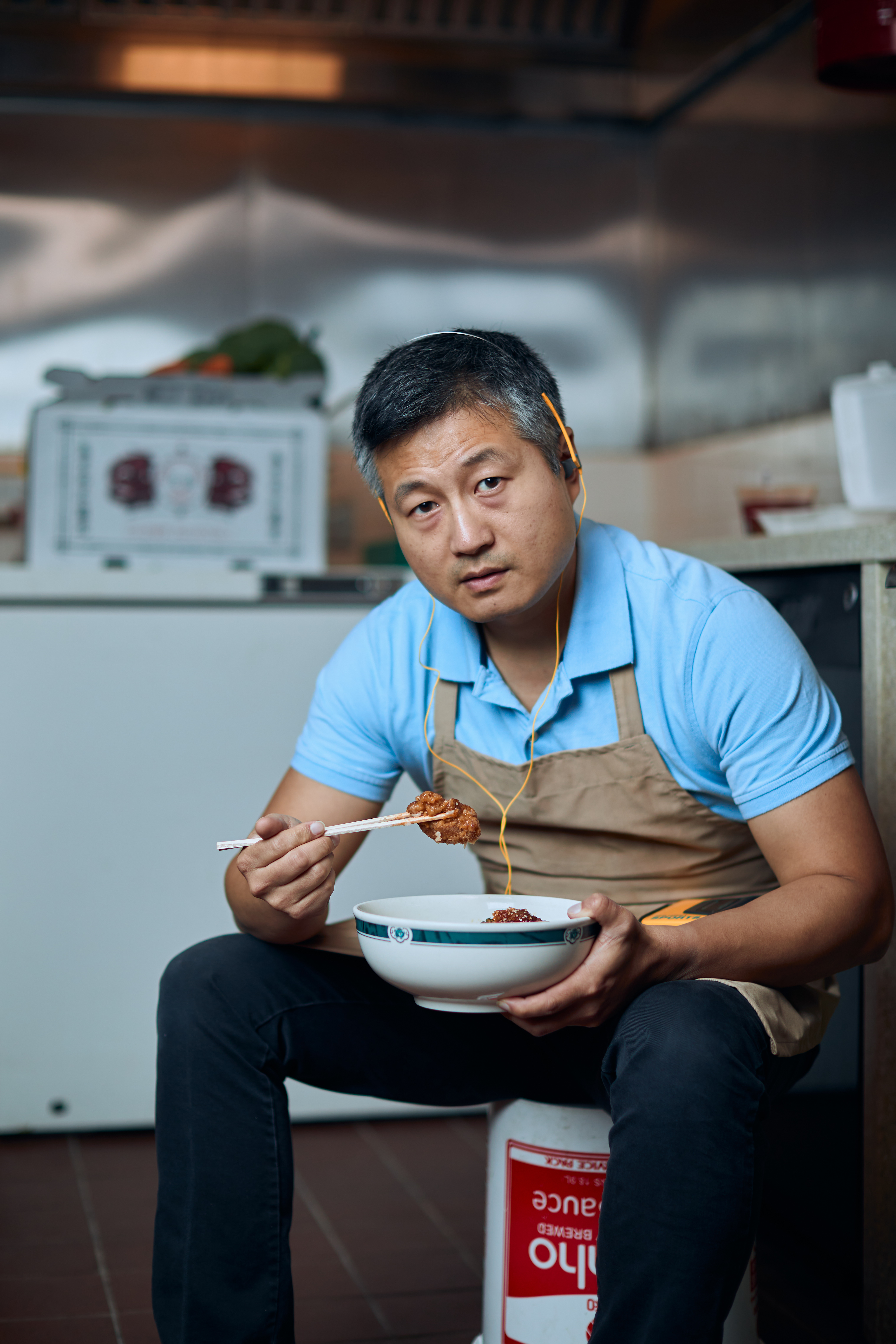 asian man eating ramen on bucket in kitchen brandon clifton atlanta photographer